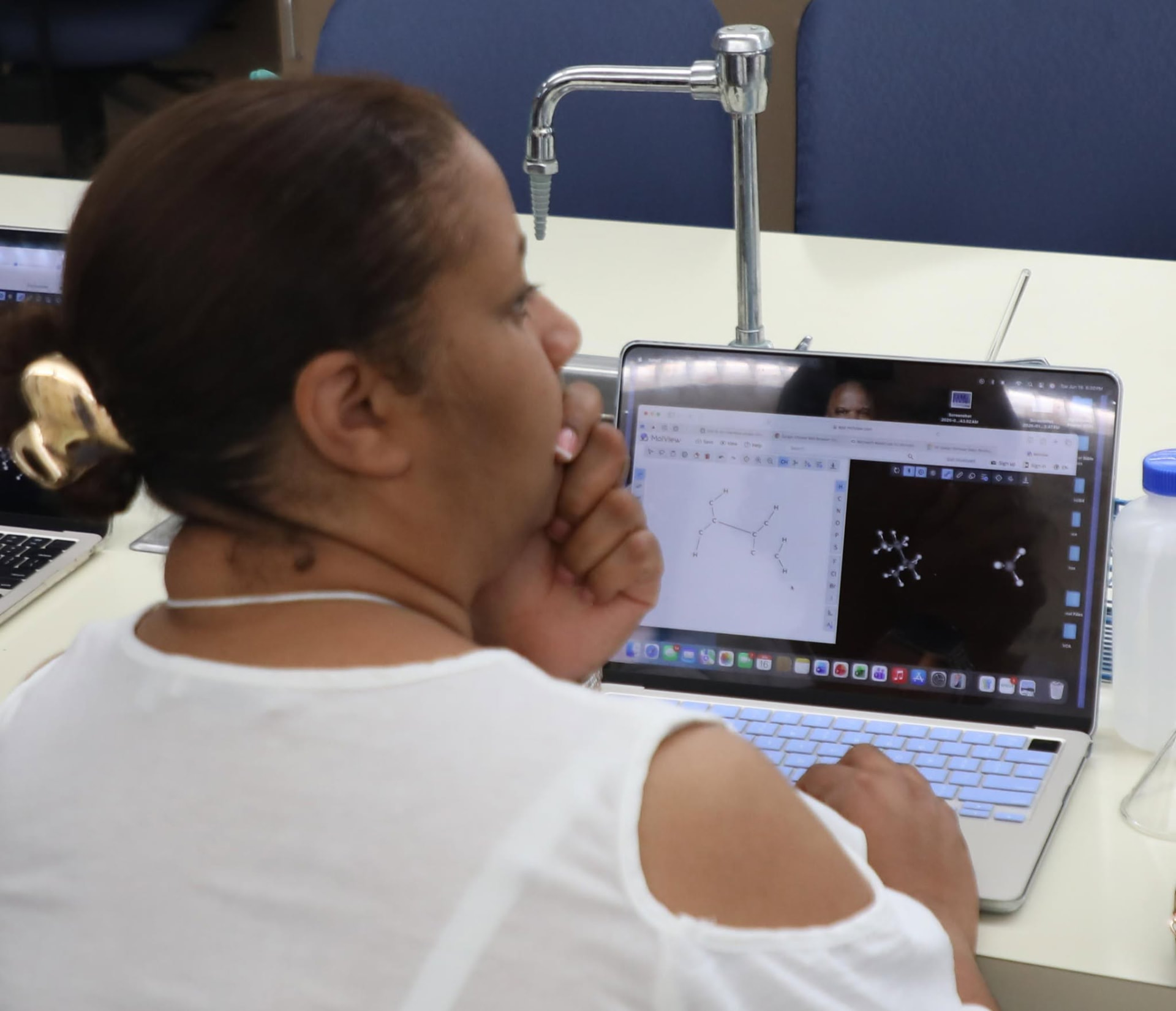 Educator exploring molecular modeling software on a laptop in a science lab