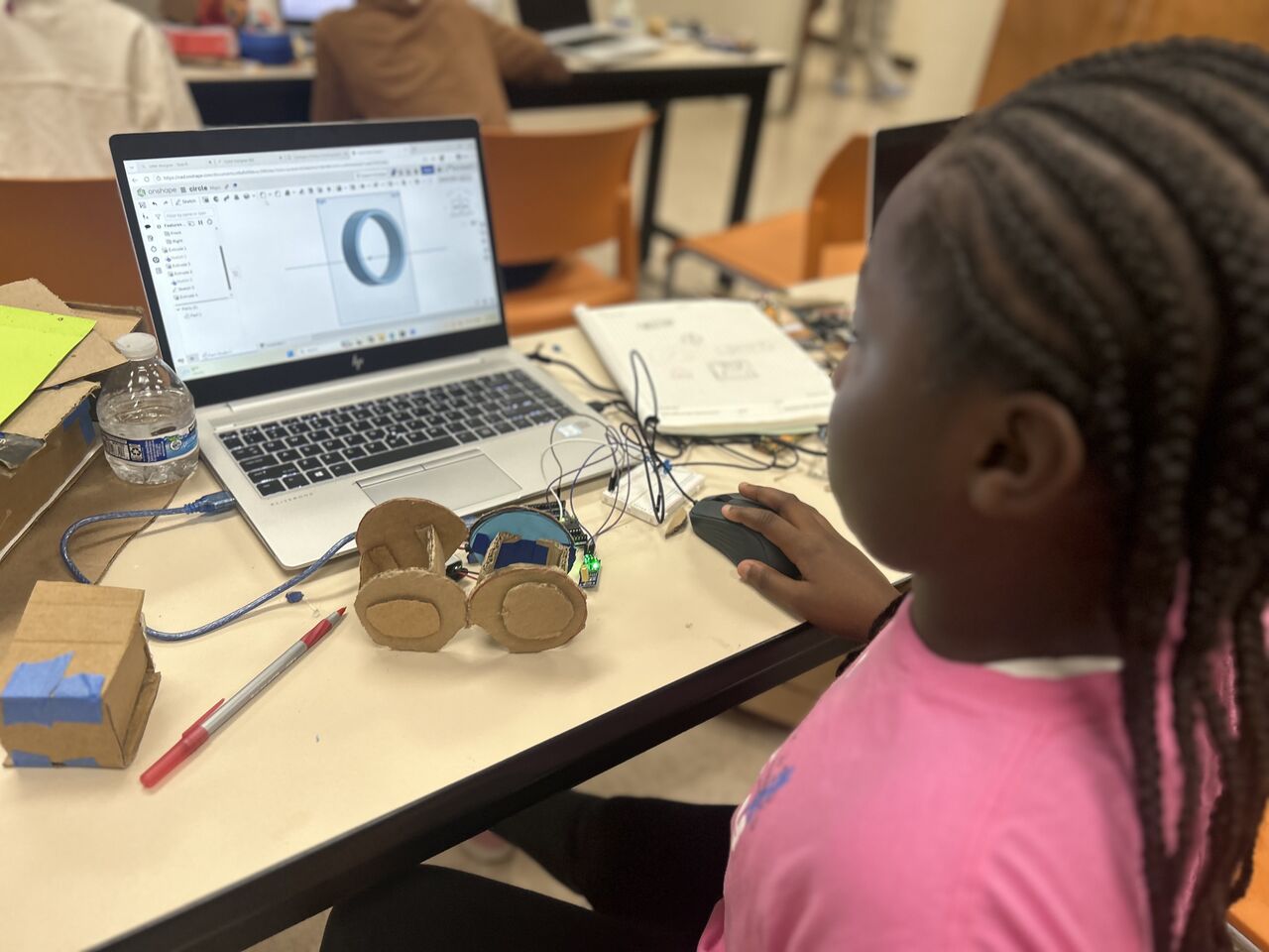 A student working on a mechatronics prototype with CAD and microcontrollers